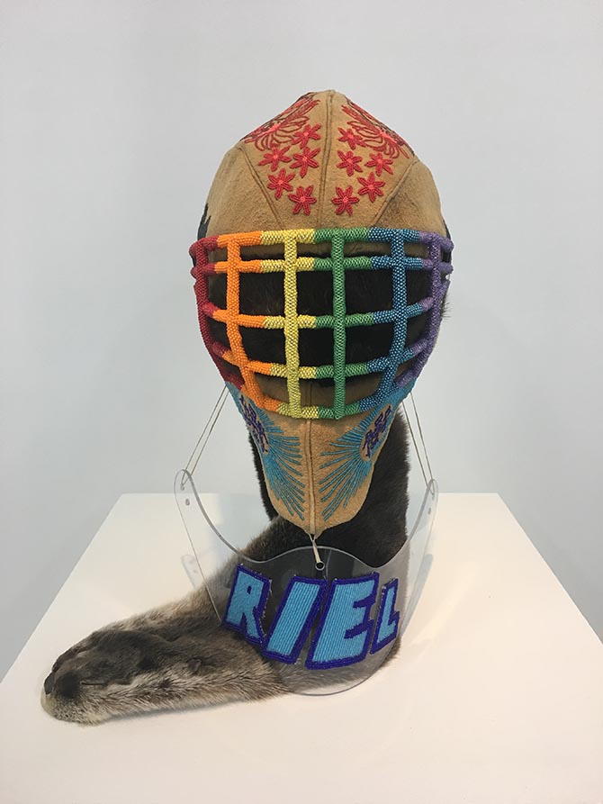 Photograph of artwork featuring beads, moose hide, a goalie helmet and otter pelt