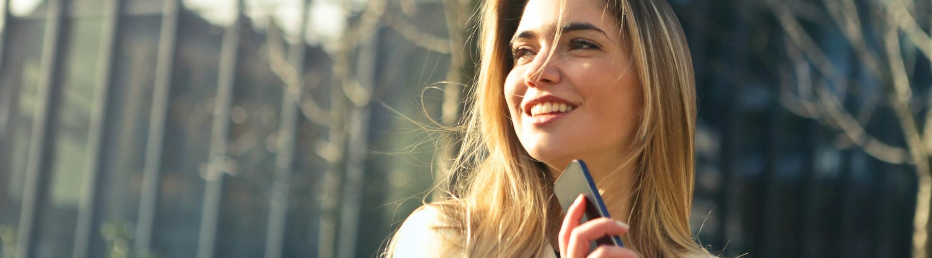 woman wearing white top holding a phone