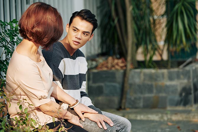 Young person talking to an adult on a bench outside