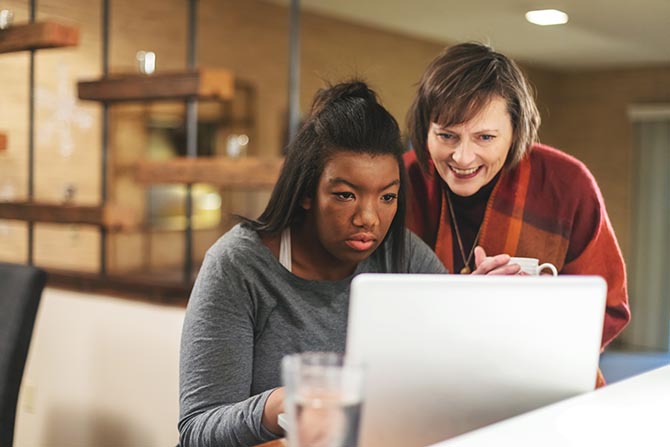 Young person and an adult looking at a laptop